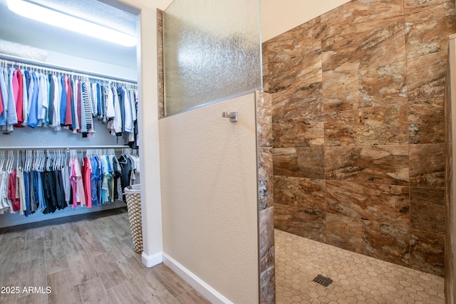 3441 N 162nd Ln, Goodyear, AZ 85395 - full bath featuring a walk in shower, wood finished floors, a textured wall, a walk in closet, and baseboards