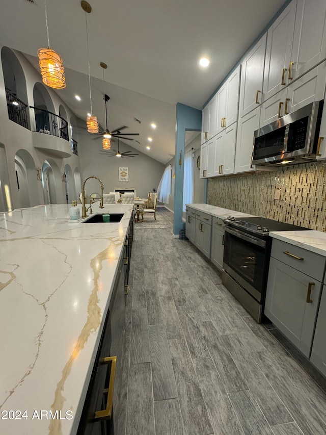 kitchen featuring stainless steel appliances, ceiling fan, sink, wood-type flooring, and decorative light fixtures