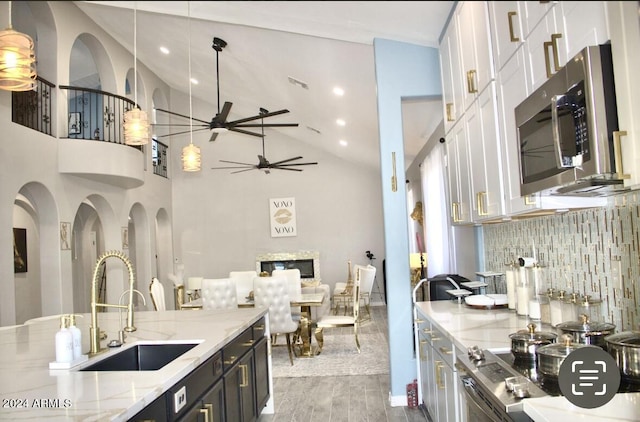 kitchen featuring high vaulted ceiling, white cabinets, hanging light fixtures, and hardwood / wood-style flooring