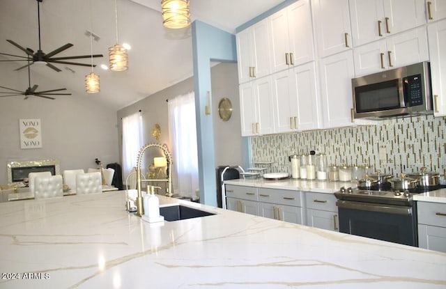 kitchen featuring range with electric stovetop, decorative backsplash, light stone countertops, and decorative light fixtures