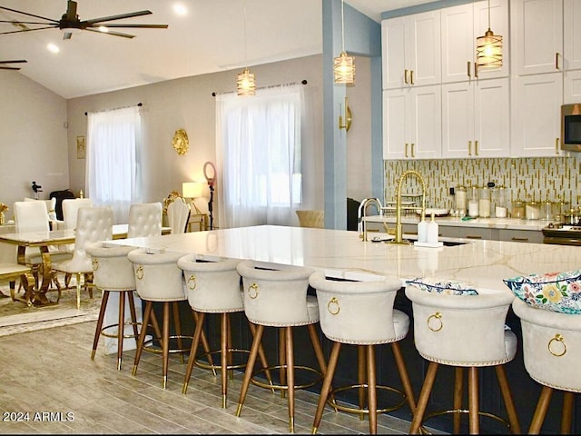 kitchen with white cabinetry, hanging light fixtures, a wealth of natural light, and light hardwood / wood-style flooring