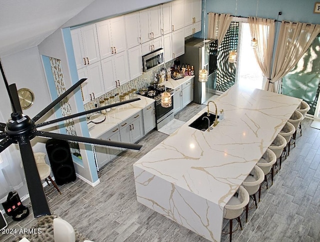 kitchen featuring sink, backsplash, a kitchen bar, appliances with stainless steel finishes, and light wood-type flooring