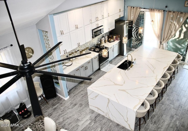 kitchen with white cabinets, appliances with stainless steel finishes, light hardwood / wood-style floors, and a breakfast bar area