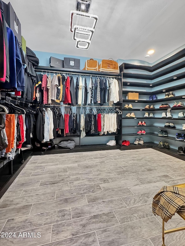 walk in closet featuring wood-type flooring and an inviting chandelier