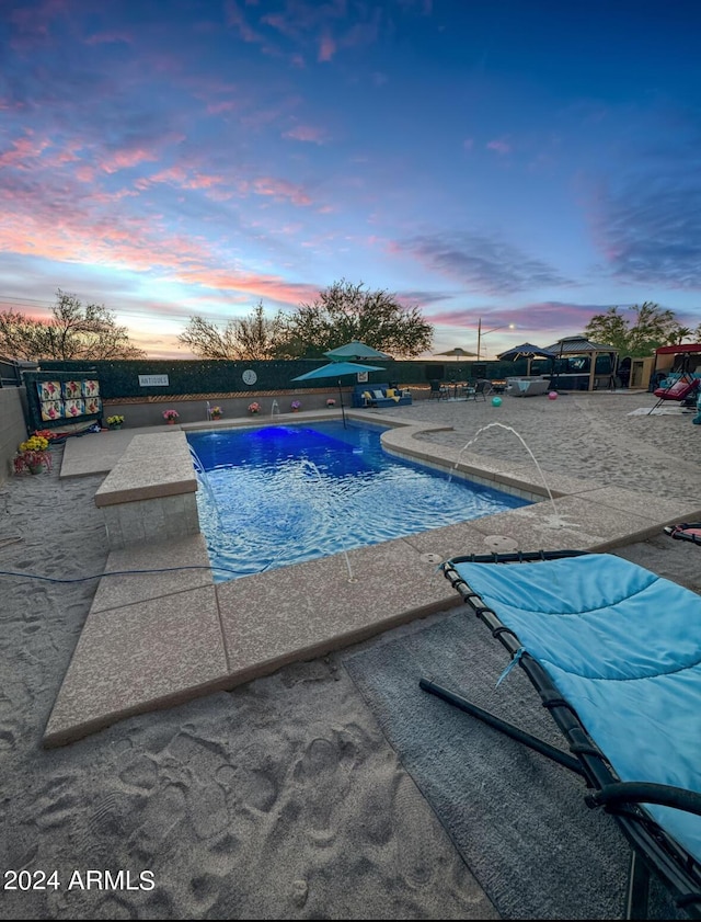 pool at dusk featuring a patio