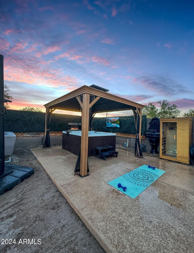 patio terrace at dusk featuring a gazebo and a hot tub