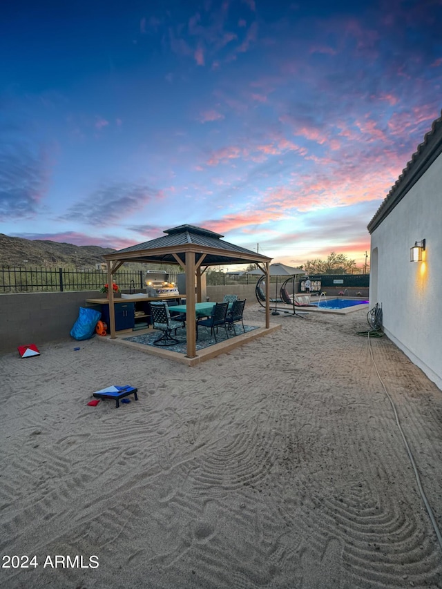 yard at dusk featuring a gazebo, a mountain view, and a patio area