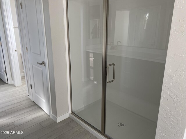 bathroom featuring wood-type flooring and a shower with shower door