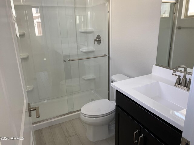 bathroom with vanity, hardwood / wood-style flooring, toilet, and a shower with shower door