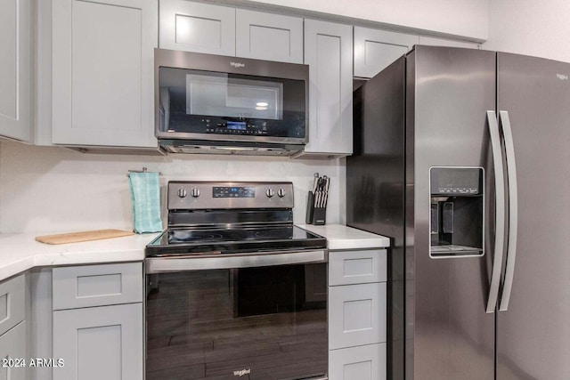 kitchen featuring stainless steel appliances, light stone counters, and white cabinetry