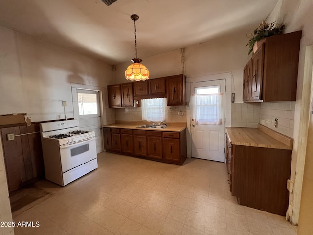 kitchen featuring sink, hanging light fixtures, white range with gas cooktop, and plenty of natural light