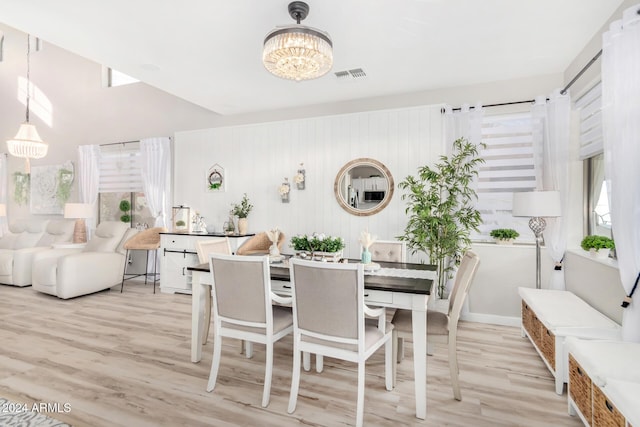 dining area with light hardwood / wood-style floors and a notable chandelier