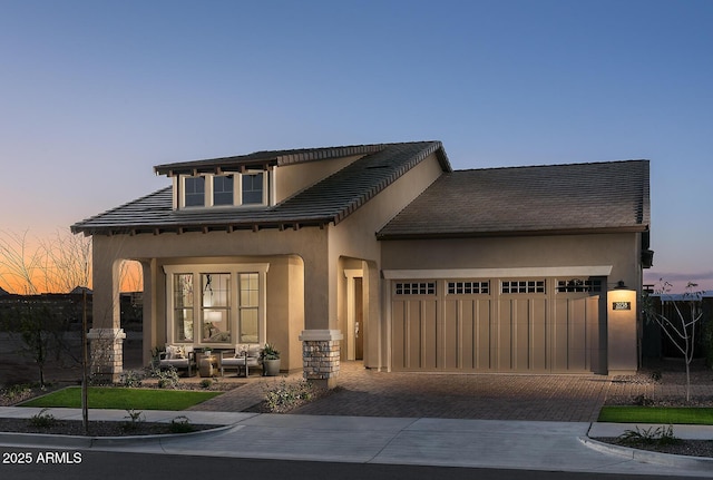 view of front of property with a garage, decorative driveway, a tiled roof, and stucco siding