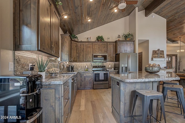 kitchen featuring wooden ceiling, appliances with stainless steel finishes, sink, ceiling fan, and light stone counters