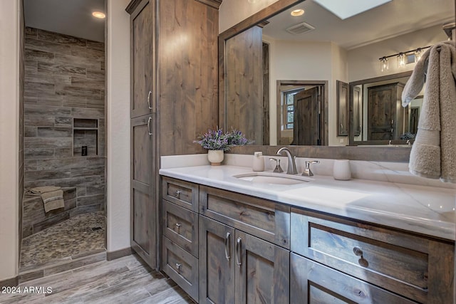 bathroom featuring tiled shower, hardwood / wood-style floors, and vanity