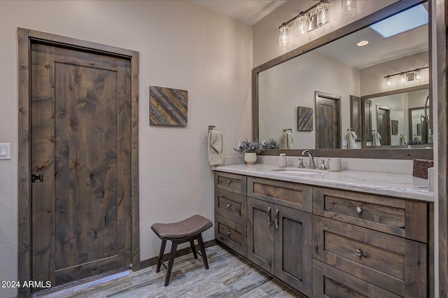 bathroom featuring a skylight, wood-type flooring, and vanity