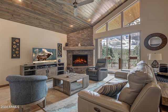 living room featuring wood ceiling, high vaulted ceiling, ceiling fan, and a stone fireplace