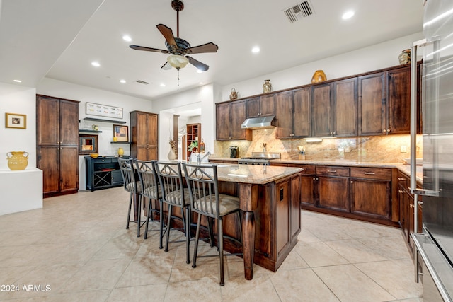 3105 S Amble Pass, Gold Canyon, AZ 85118 - kitchen with ceiling fan, a kitchen island, backsplash, and light stone countertops