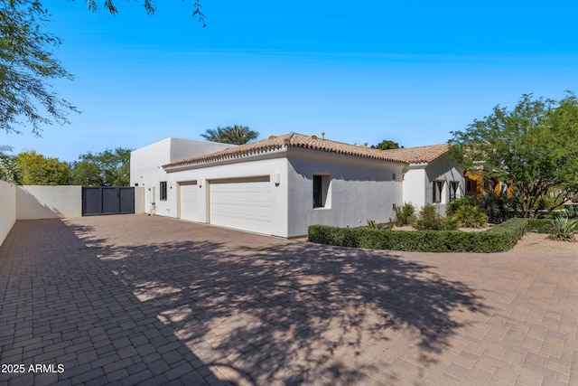 6648 E Horseshoe Rd, Paradise Valley, AZ 85253 - view of side of property featuring a garage, decorative driveway, stucco siding, a gate, and a tiled roof