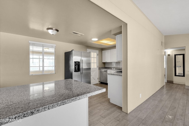 kitchen featuring appliances with stainless steel finishes, light wood-type flooring, visible vents, and decorative backsplash