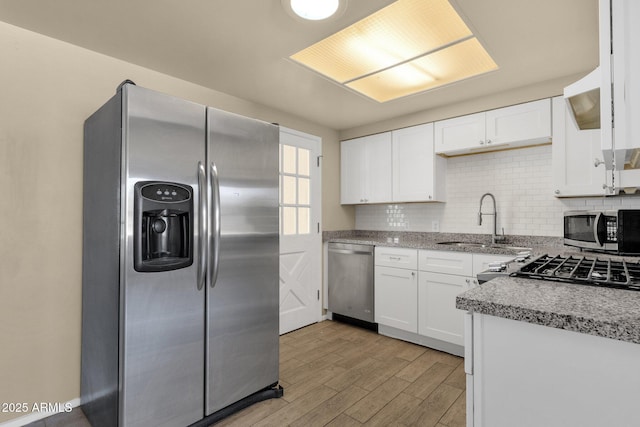 kitchen featuring stainless steel appliances, white cabinets, a sink, and light wood-style flooring