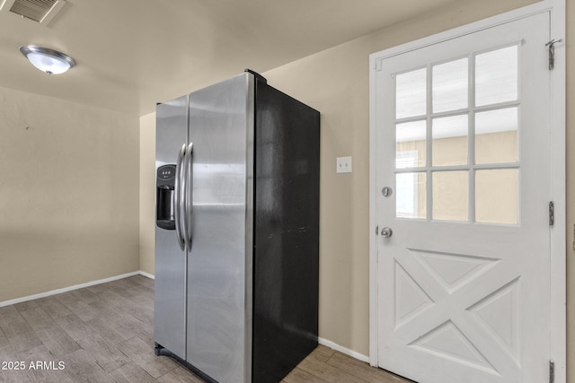 kitchen with stainless steel fridge, visible vents, light wood-style flooring, and baseboards