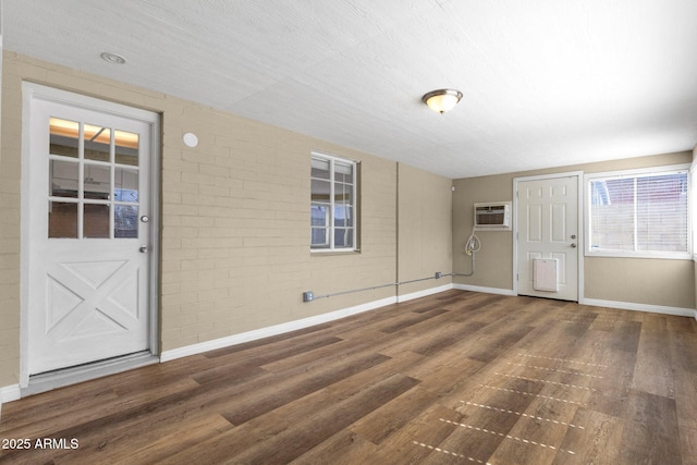 entryway featuring an AC wall unit, baseboards, brick wall, and wood finished floors