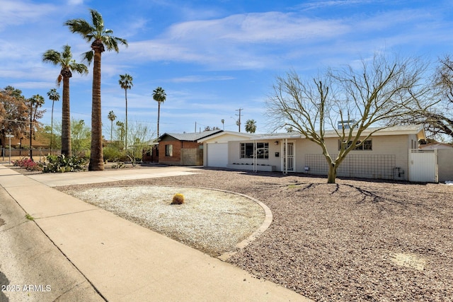 ranch-style house featuring a garage, concrete driveway, fence, and a gate