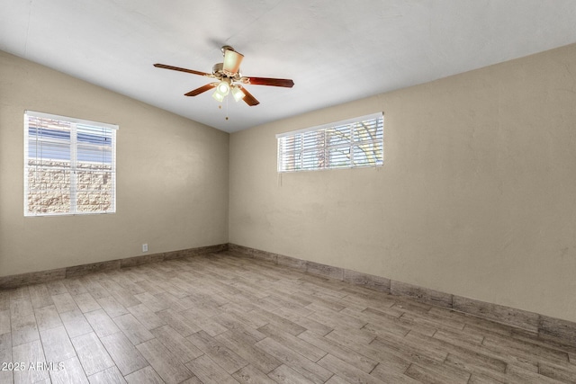 empty room featuring lofted ceiling, wood finished floors, a ceiling fan, and baseboards