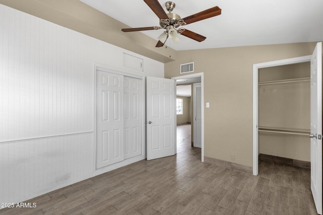 unfurnished bedroom featuring lofted ceiling, a closet, visible vents, and wood finished floors