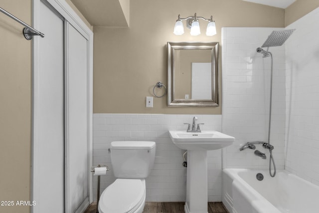 full bath with shower / bathtub combination, toilet, a wainscoted wall, a sink, and tile walls