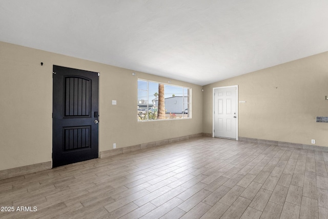 interior space featuring vaulted ceiling, wood finished floors, and baseboards