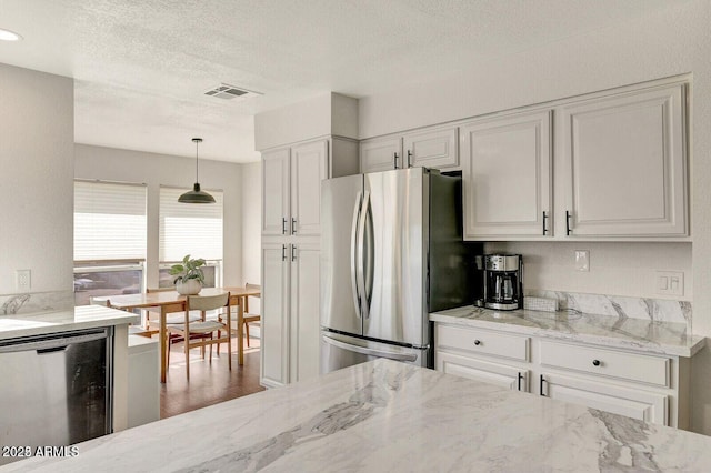 101 N 7th St Unit 225, Phoenix, AZ 85034 - kitchen with stainless steel appliances, light stone countertops, white cabinets, a textured ceiling, and decorative light fixtures