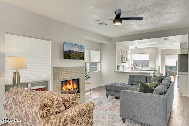101 N 7th St Unit 225, Phoenix, AZ 85034 - living room with ceiling fan, a textured ceiling, and a warm lit fireplace