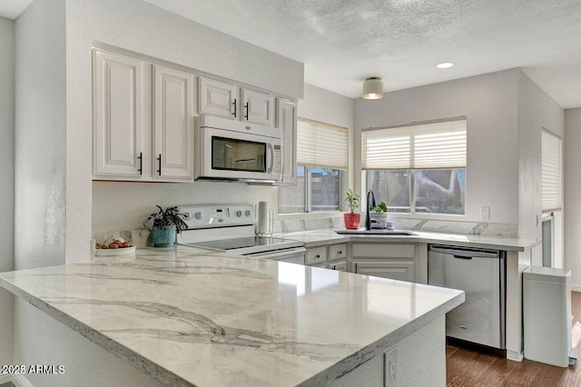 101 N 7th St Unit 225, Phoenix, AZ 85034 - kitchen featuring white appliances, dark wood finished floors, white cabinets, a peninsula, and light stone counters