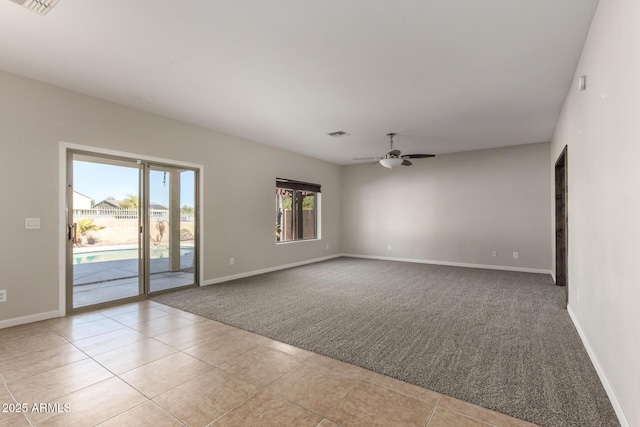 spare room featuring light carpet, visible vents, baseboards, ceiling fan, and light tile patterned flooring