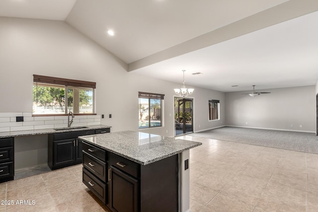 kitchen featuring a sink, baseboards, open floor plan, a center island, and decorative light fixtures