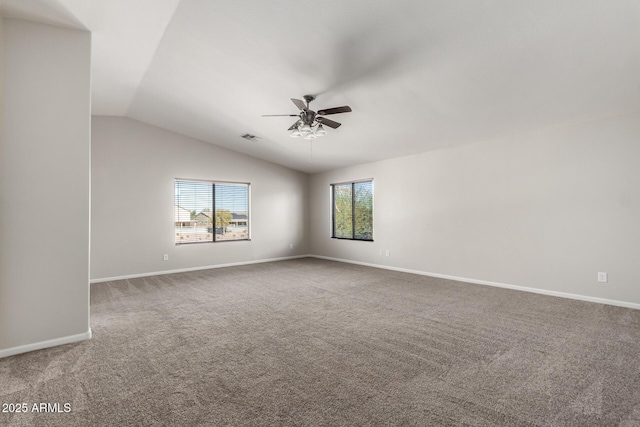 empty room featuring lofted ceiling, carpet, and a wealth of natural light