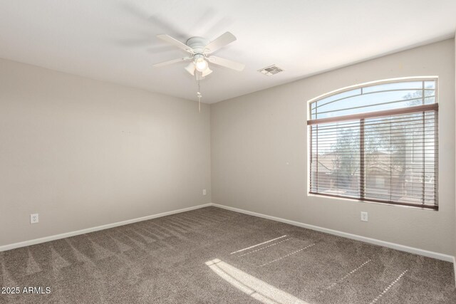 spare room featuring carpet floors, baseboards, visible vents, and ceiling fan