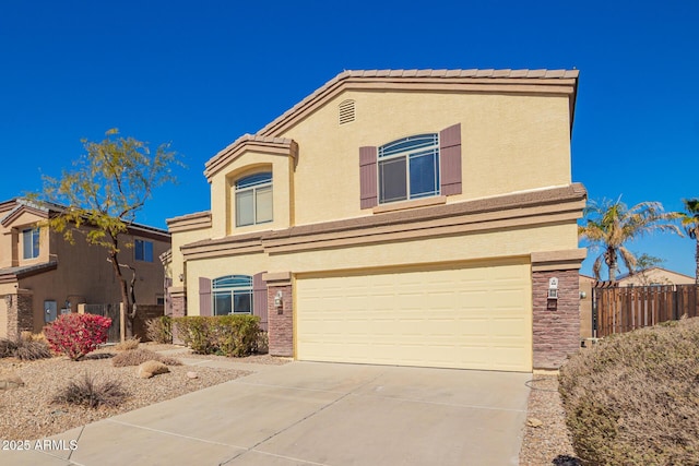 traditional home with an attached garage, driveway, fence, and stucco siding