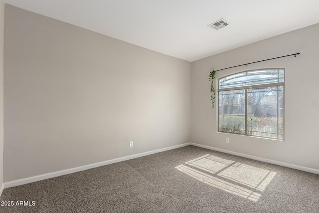 spare room featuring carpet floors, visible vents, and baseboards