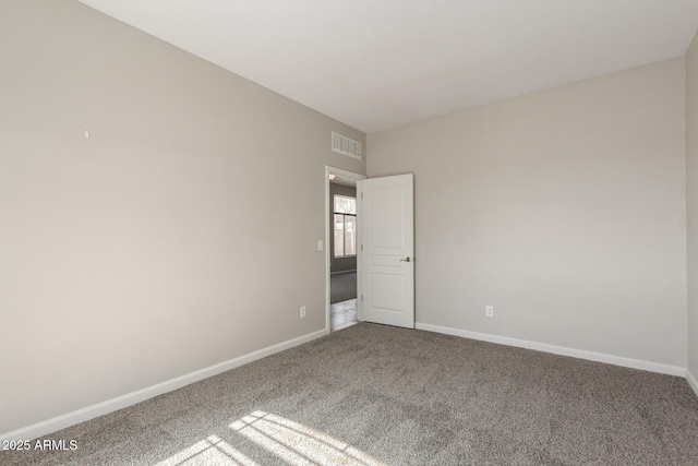 carpeted spare room with visible vents and baseboards