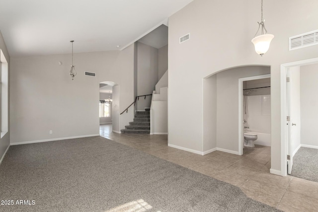 interior space featuring carpet floors, stairway, visible vents, and arched walkways