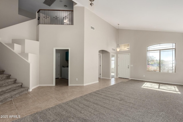 unfurnished living room featuring light tile patterned floors, stairs, visible vents, and arched walkways