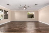 unfurnished room featuring crown molding, baseboards, and wood finished floors