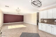 kitchen featuring light tile patterned floors, tasteful backsplash, white cabinets, and crown molding