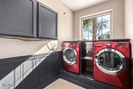 clothes washing area featuring independent washer and dryer and cabinet space