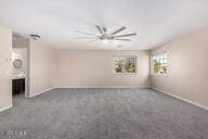 unfurnished living room with ceiling fan, baseboards, and carpet flooring