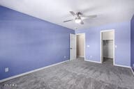 unfurnished bedroom with a ceiling fan, a walk in closet, a closet, and baseboards