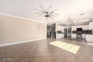 unfurnished living room with a ceiling fan and baseboards